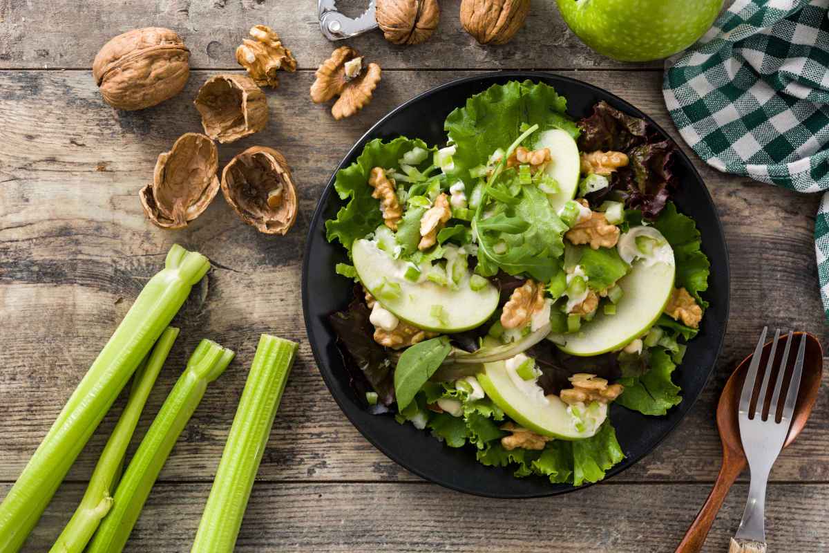 piatto nero con insalata di sedano e mele con noci