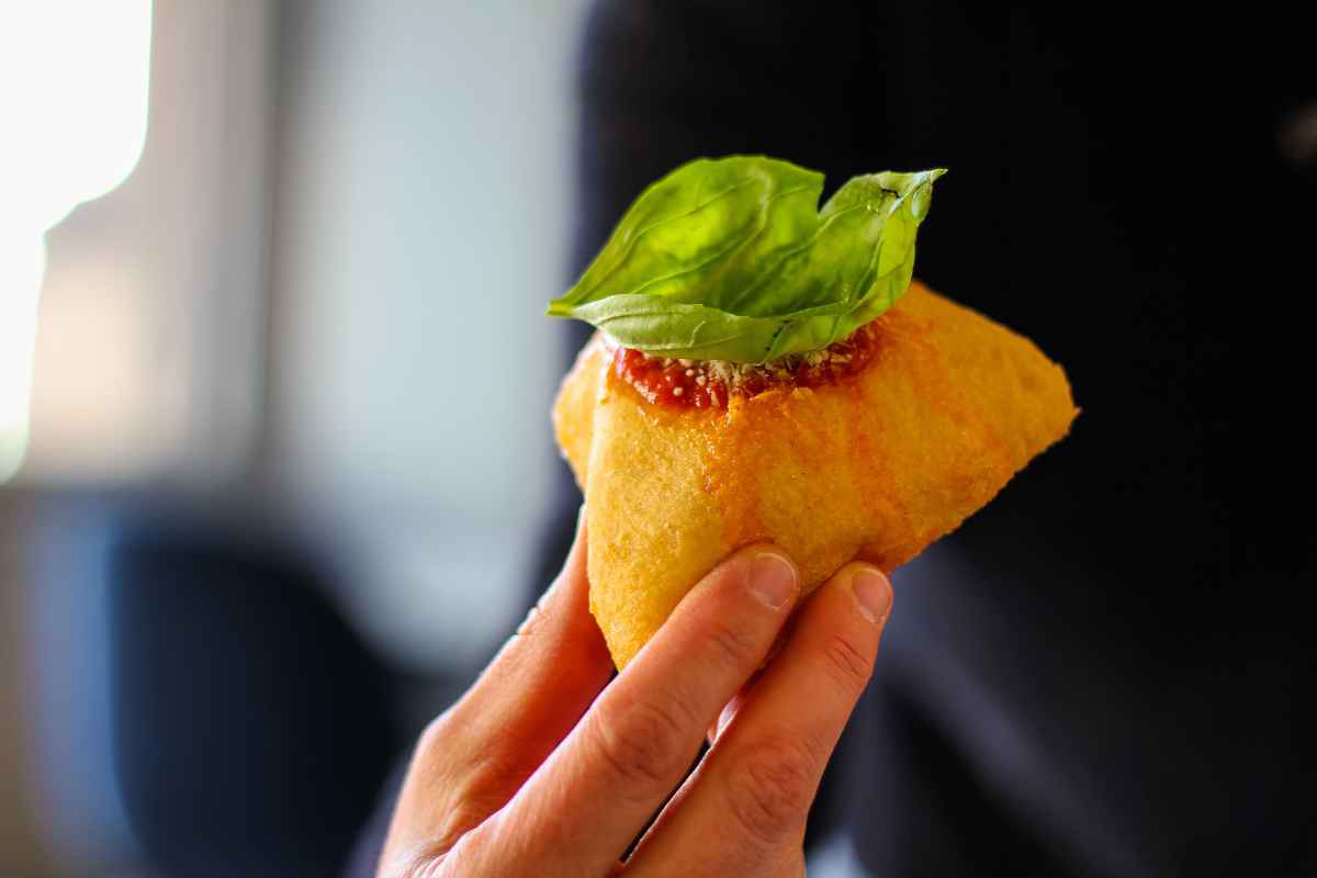 uomo tiene in mano una pizza fritta napoletana con foglia di basilico fresco