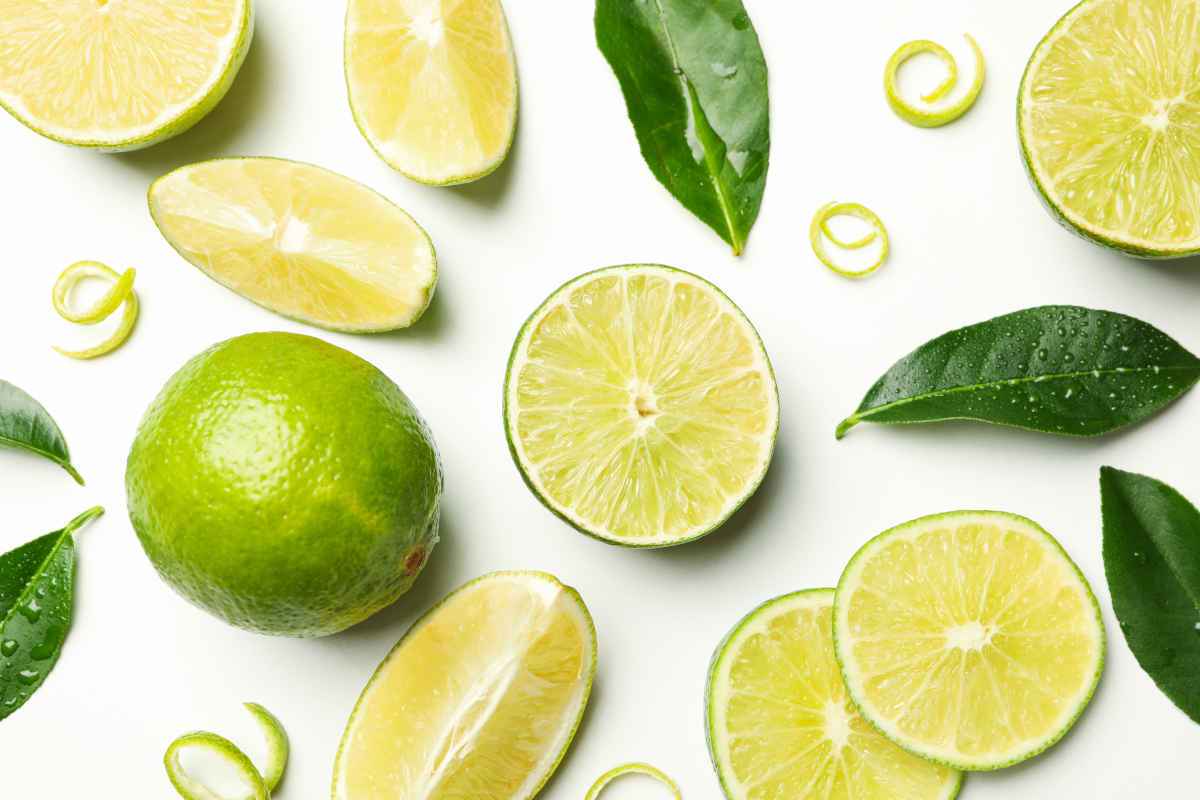 lime intero e a spicchi su tavolo bianco