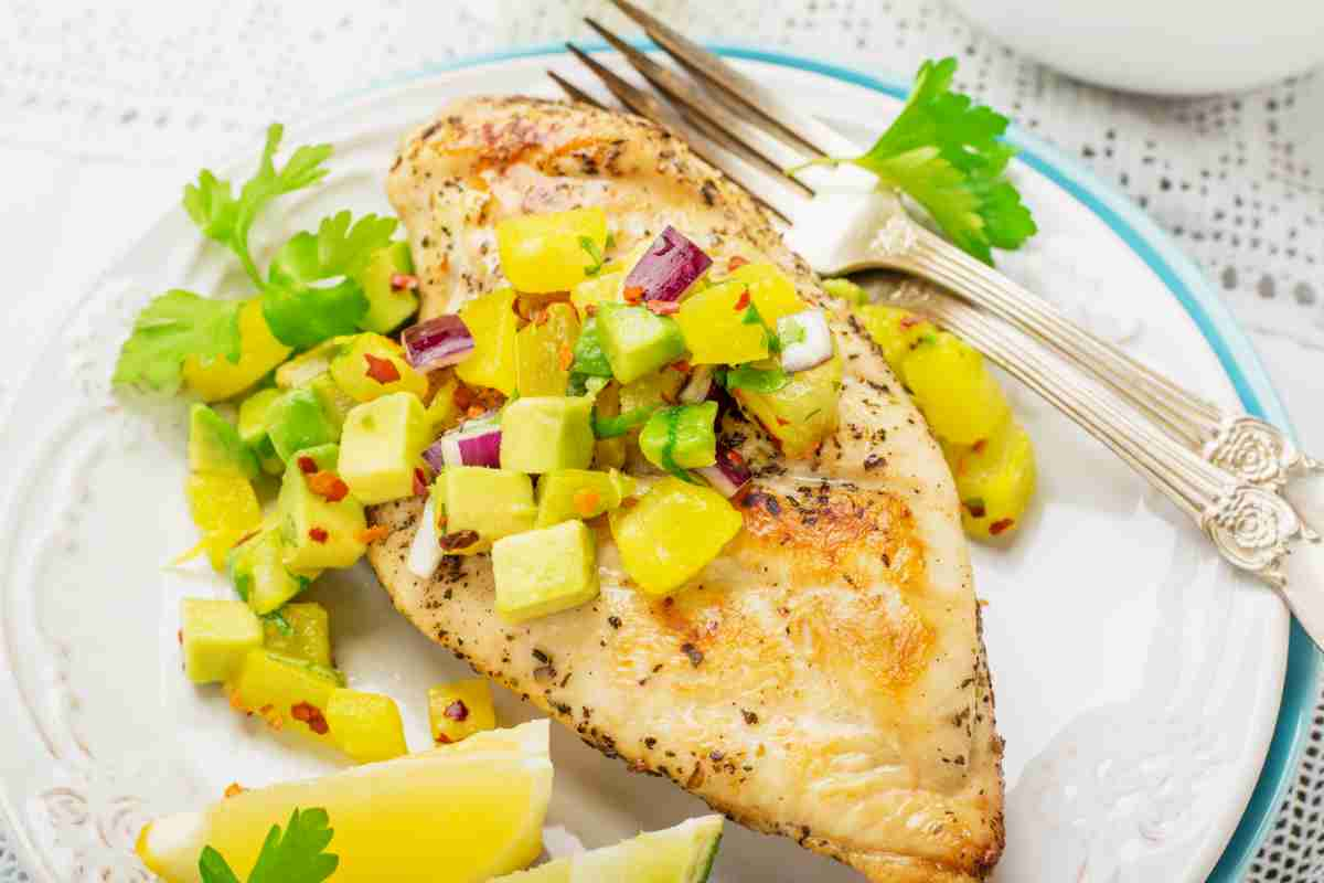 petto di pollo alla griglia con salsa di mango e spicchio di limone in un piatto