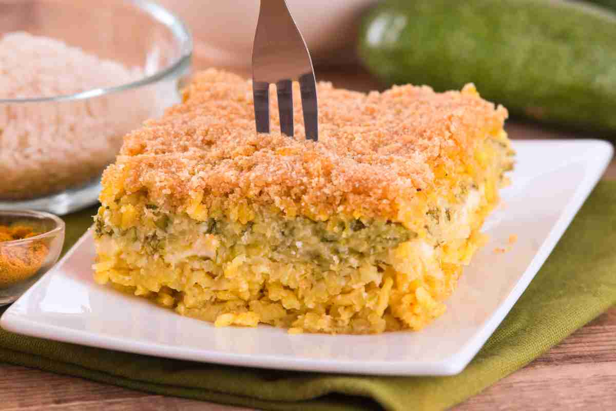 Timballo di riso e zucchine su piatto quadrato con forchetta in mezzo