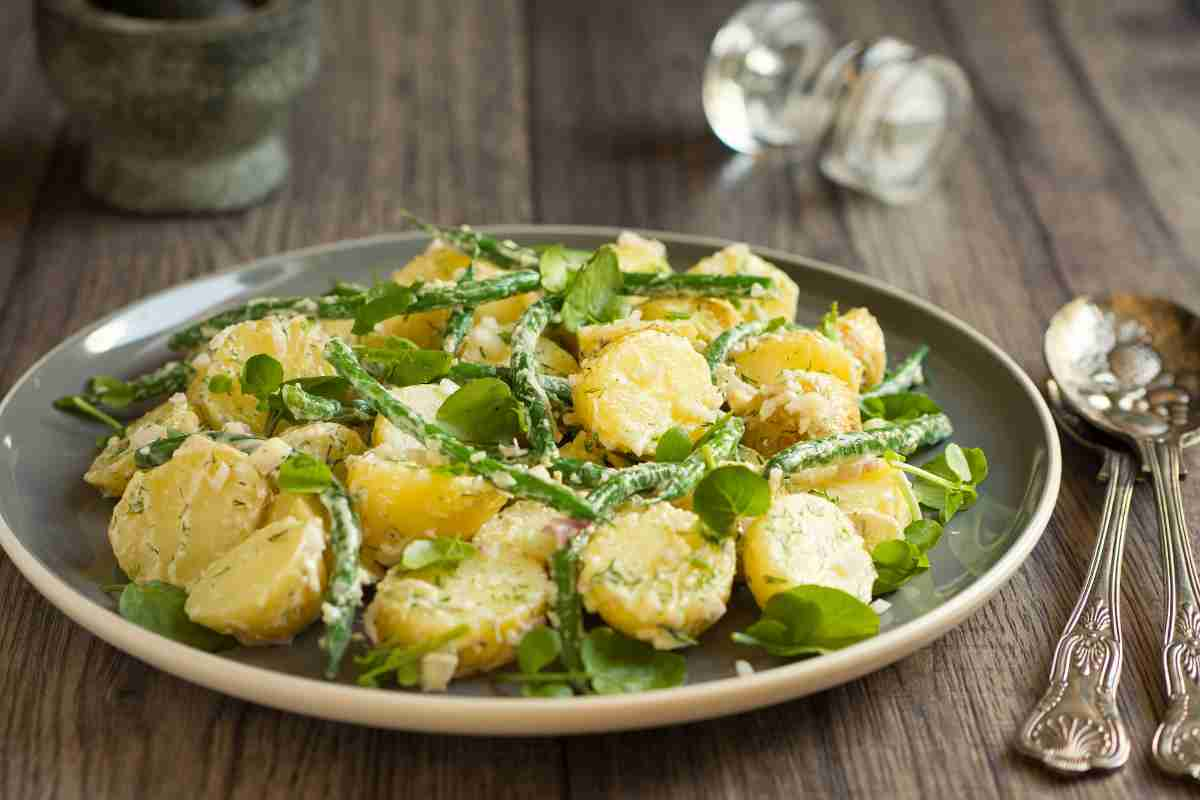 Fagiolini e patate ripassati in padella conditi con salsa in un piatto