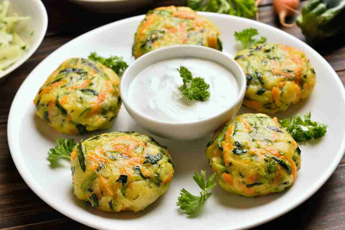 piatto con 5 medaglioni di zucchine e carote e una ciotola di salsa al centro