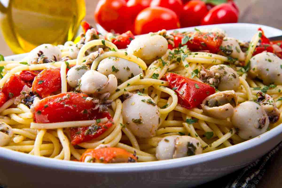 Spaghetti seppioline e pomodoro con prezzemolo in un vassoio ovale