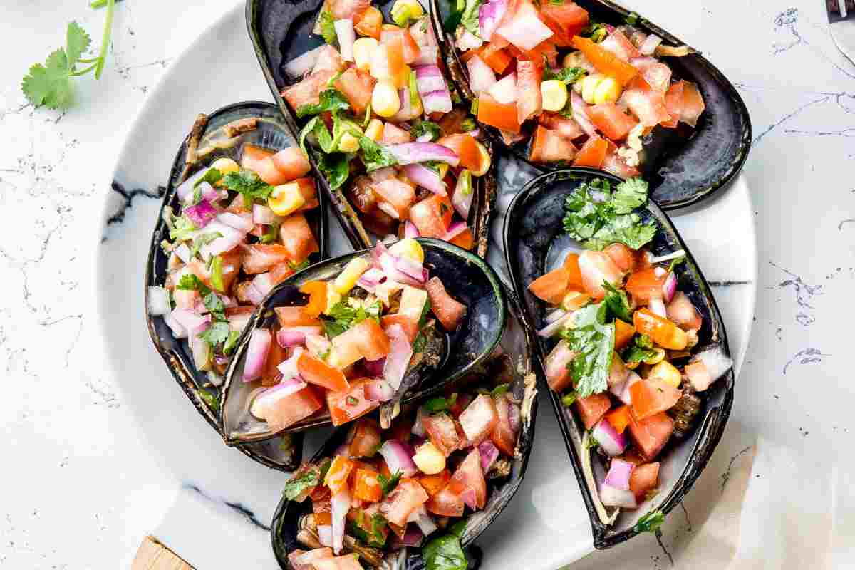 Cozze ripiene estive con insalata di verdure in un piatto bianco