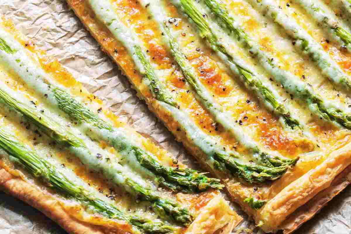 Crostata salata con asparagi in una teglia con carta forno