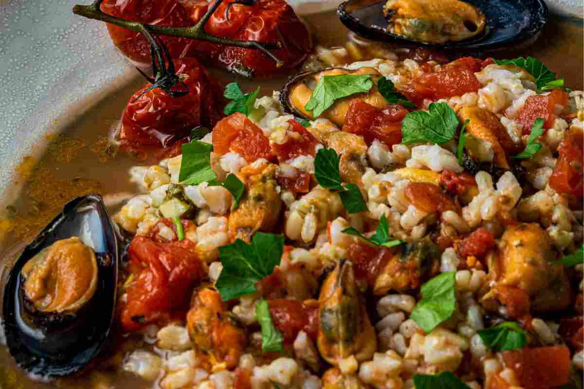 Orzo con le cozze guarnito con prezzemolo in un piatto