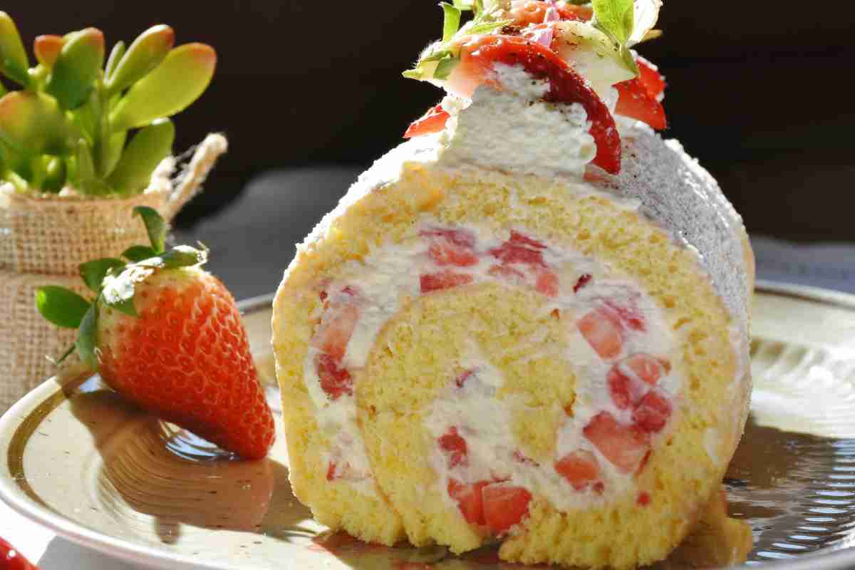 Rotolo di pan di Spagna farcito con panna e fragole a pezzi