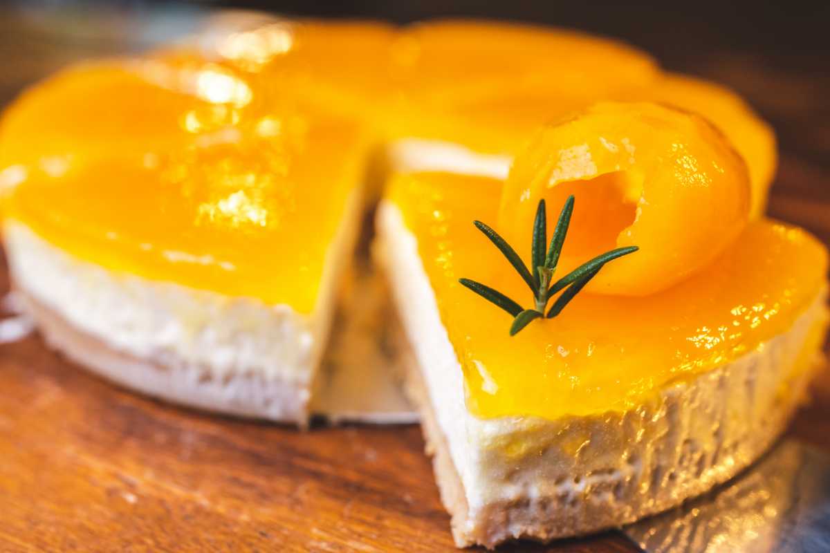 Cheesecake al mango tagliata a fette con un rametto di rosmarino come decorazione