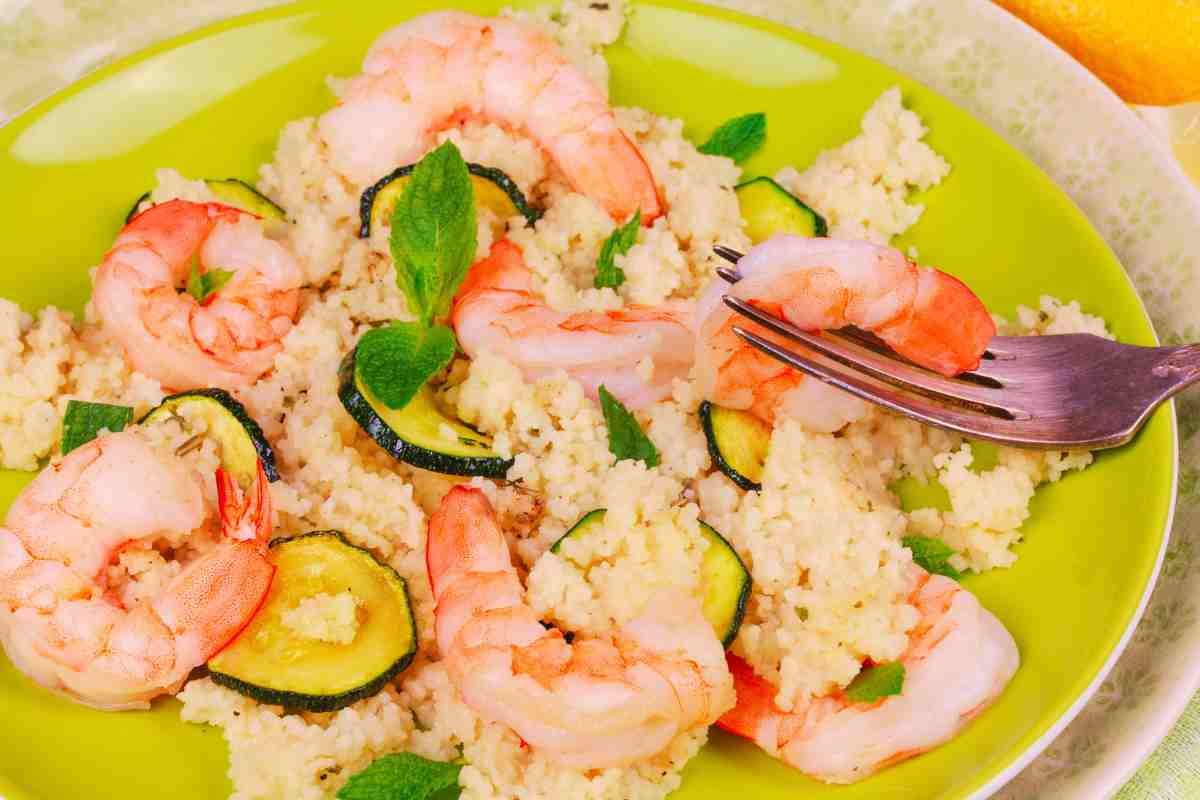 Cous cous zucchine e gamberetti in un piatto verde