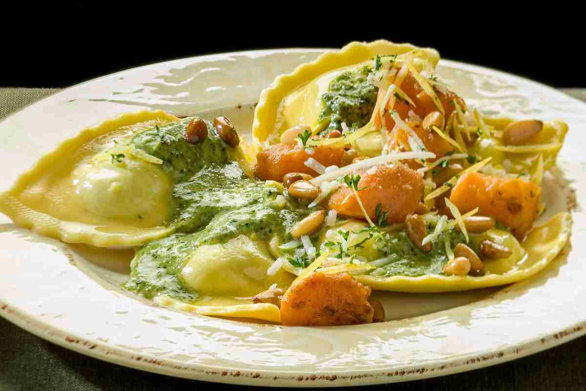 Piatto con pansotti liguri conditi con pesto, pinoli tostati e cubetti di zucca