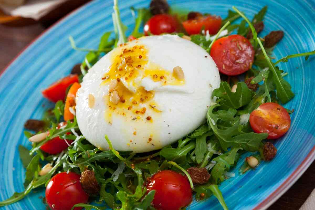 insalata con burrata, rucola e pachino su un piatto azzurro