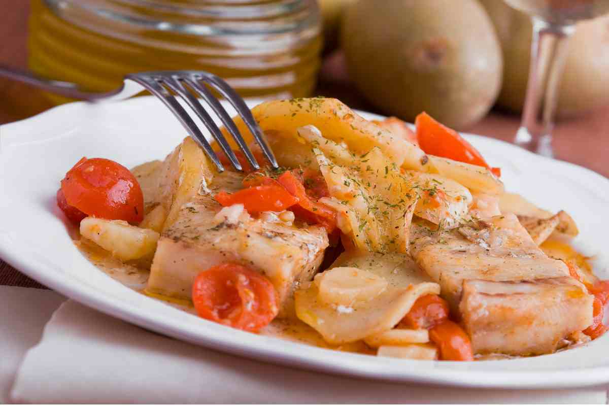 Baccalà alla romana con pomodoro e patate in un piatto bianco