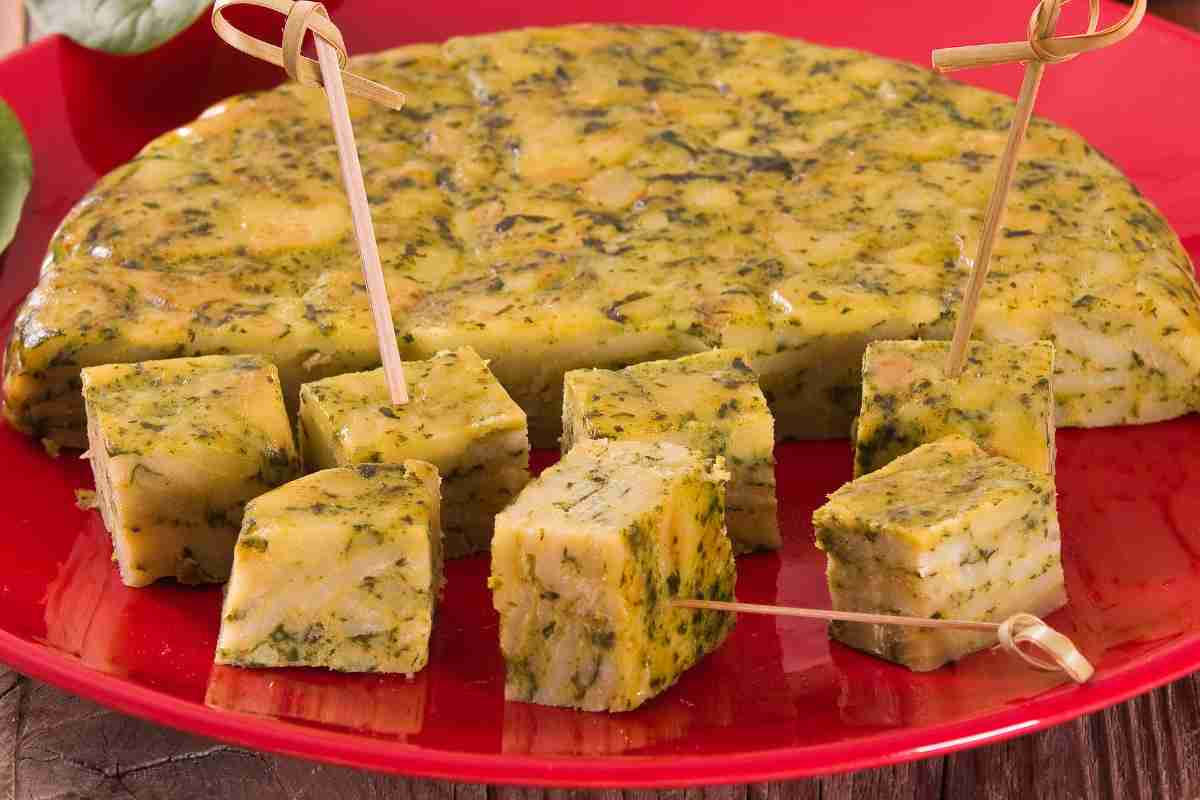 Frittata pesto e patate tagliata a cubetti in un piatto rosso