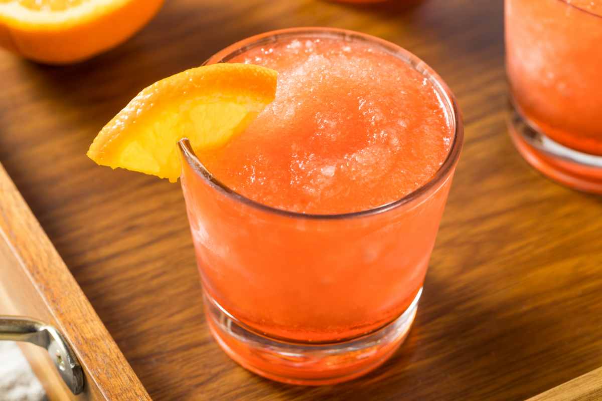 Orange Spritz Frozen con fetta di arancia sul bicchiere servito su un tagliere di legno