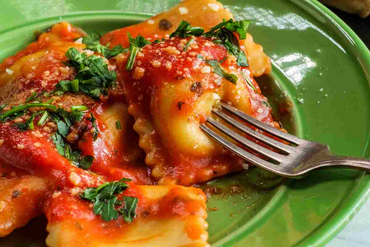 Tortelli alla marinara in un piatto verde spolverati con formaggio grattugiato