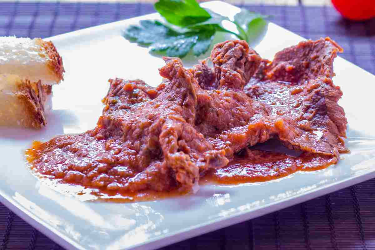 Carne alla pizzaiola in un piatto bianco con vicino del pane